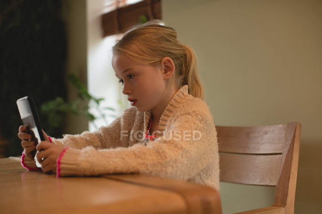 Linda chica usando tableta digital en la sala de estar en casa - foto de stock