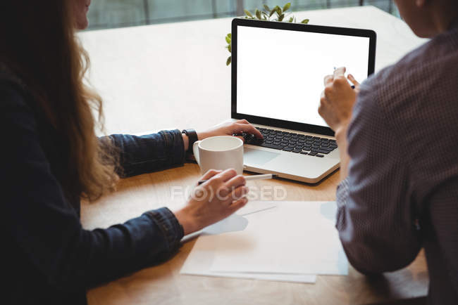 Керівники бізнесу обговорюють ноутбук в офісі — стокове фото