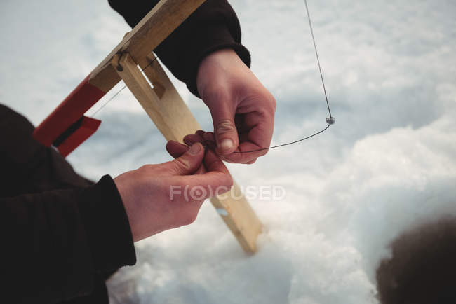 Gros plan des mains d'un pêcheur sur glace qui appâte — Photo de stock