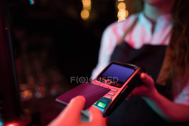 Cliente haciendo el pago a través de tarjeta de crédito en el mostrador en bar - foto de stock