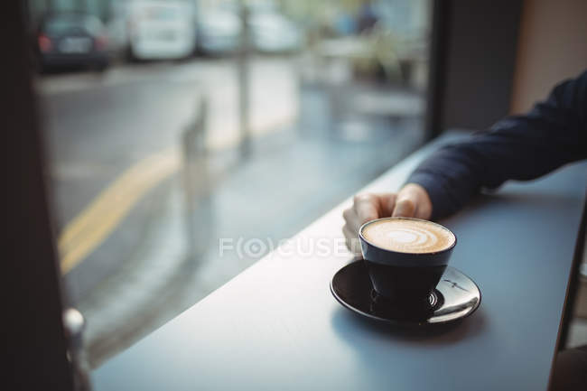 Main d'un cadre tenant un café au comptoir de la cafétéria — Photo de stock