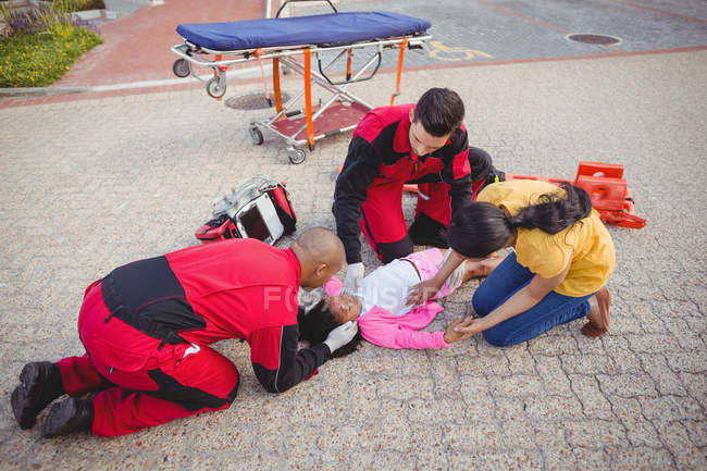 Los paramédicos examinan a una chica herida en la calle - foto de stock