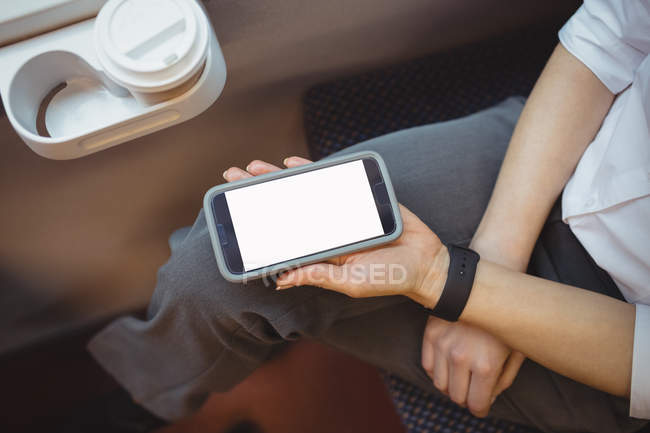 Mid-section of businesswoman holding mobile phone while travelling — Stock Photo