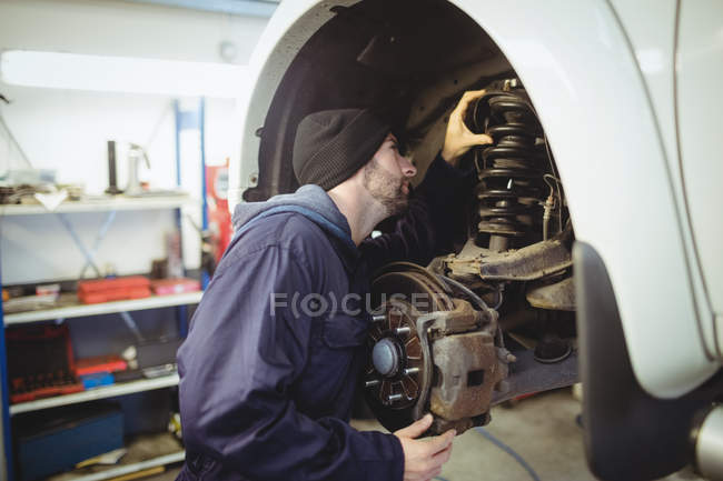 Mécanicien examinant un frein à disque de roue de voiture dans le garage de réparation — Photo de stock