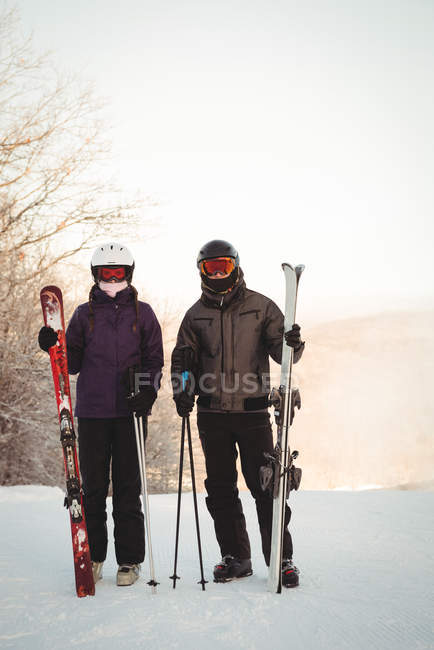 Skier couple with skies standing on snowy landscape in ski resort — Stock Photo