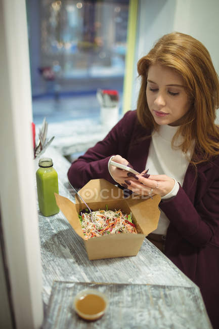 Donna che scatta foto di insalata sul cellulare nel ristorante — Foto stock
