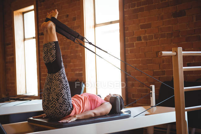 Mujer practicando pilates en reformador en gimnasio - foto de stock
