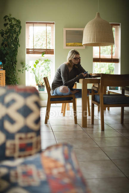 Женщина использует мобильный телефон, сидя дома — стоковое фото