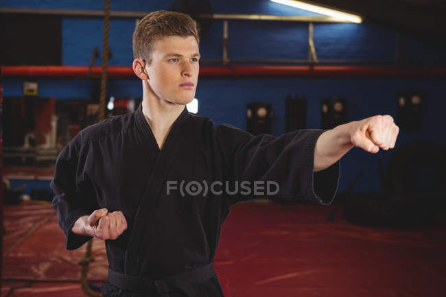 Young adult karate player performing karate stance in fitness studio — Stock Photo