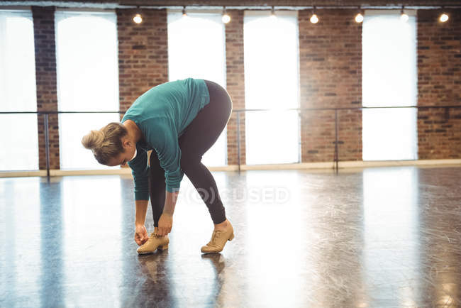 Женщина завязывала шнурки в танцевальной студии — стоковое фото