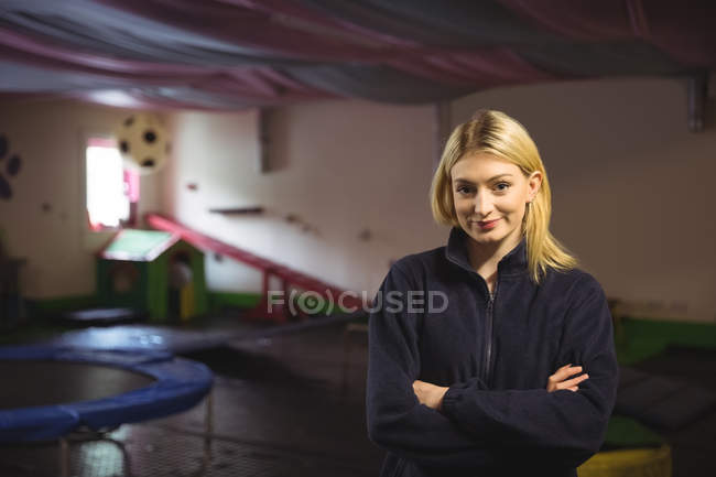 Portrait of a woman standing with her arms crossed at dog care center — Stock Photo