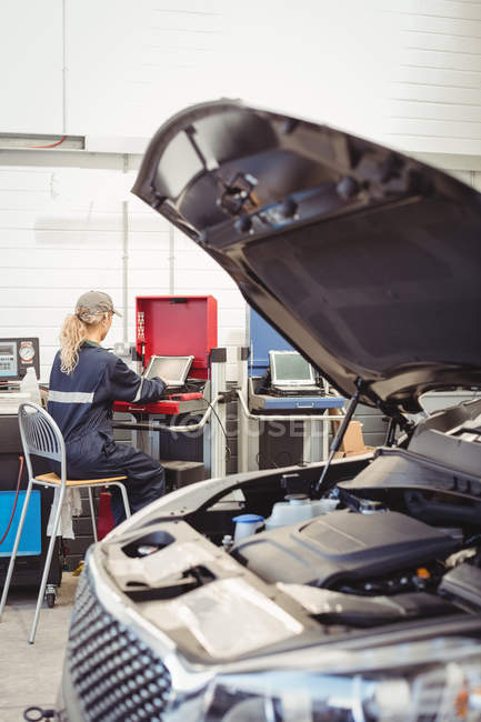 Mecânico feminino usando laptop na garagem de reparação — Fotografia de Stock