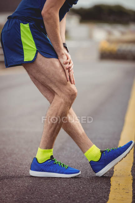 Человек, растягивающий ногу на дороге в сельской местности — стоковое фото
