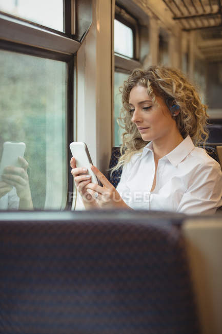 Mujer de negocios adulta mediana usando un teléfono inteligente mientras viaja - foto de stock
