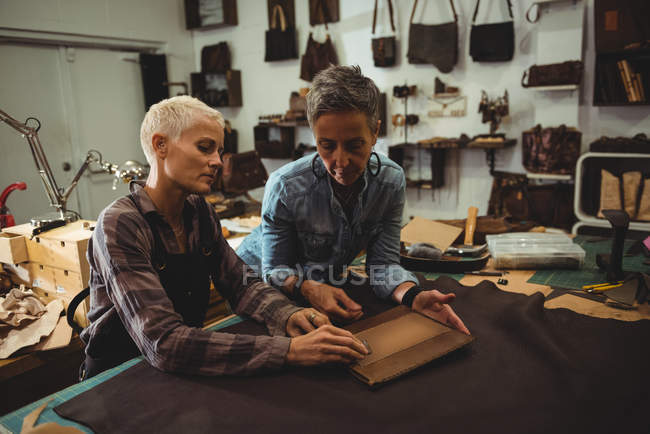 Craftswomen preparing leather cover for digital tablet — Stock Photo