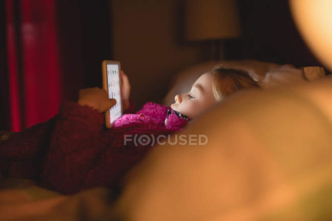Niña descansando y usando tableta digital en el dormitorio en casa - foto de stock