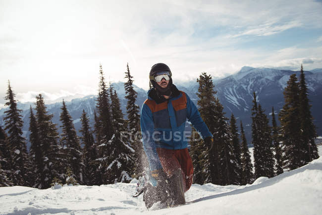Hombre caminando en la montaña cubierta de nieve contra los árboles - foto de stock