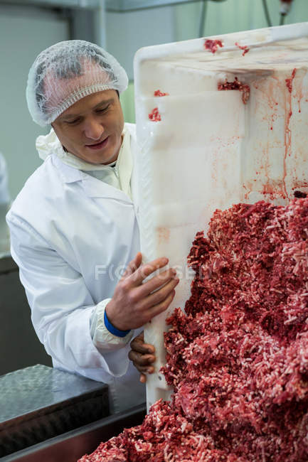 Butcher emptying tray with minced meat at meat factory — Stock Photo