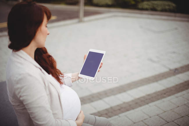 Embarazada mujer de negocios sosteniendo tableta digital en oficinas - foto de stock