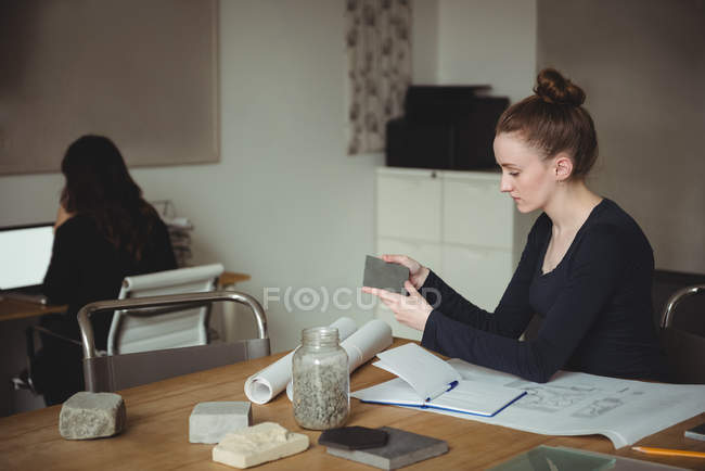 Business executive looking at stone slab in office — Stock Photo