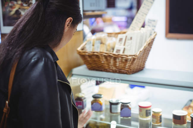 Mujer mirando la exhibición de comida en el supermercado - foto de stock