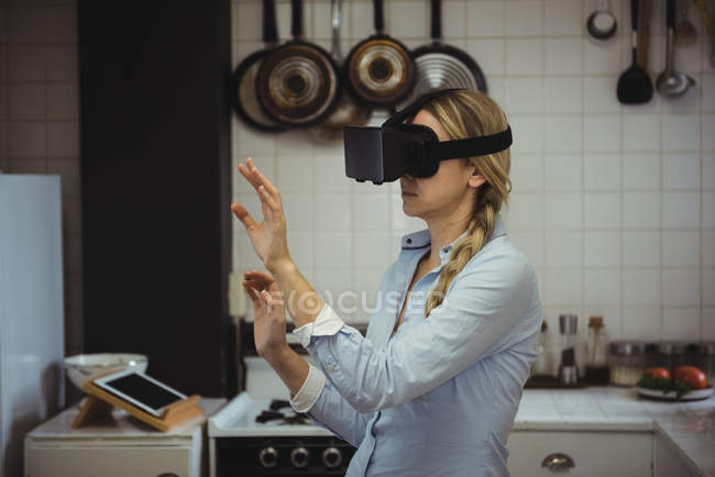 Donna che sperimenta la realtà virtuale auricolare in cucina a casa — Foto stock