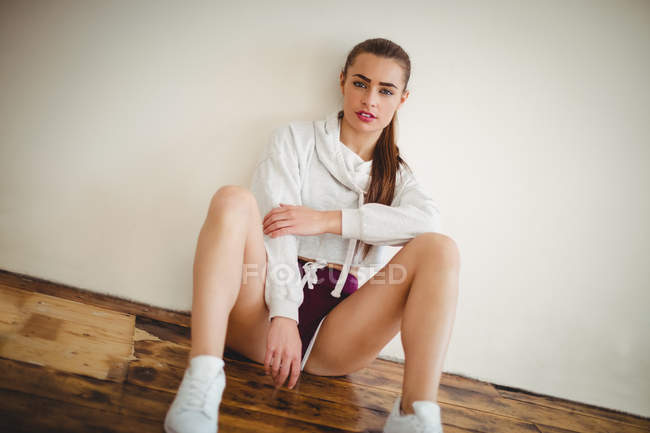 Jeune femme décontractée assise sur le sol dans un studio de danse — Photo de stock