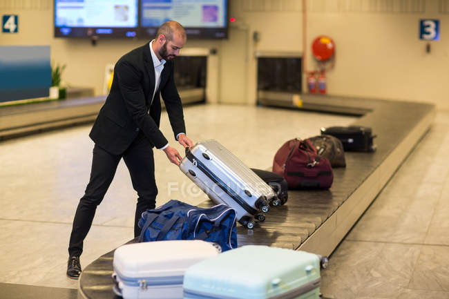 Uomo d'affari ritirare i bagagli dalla zona ritiro bagagli in aeroporto — Foto stock