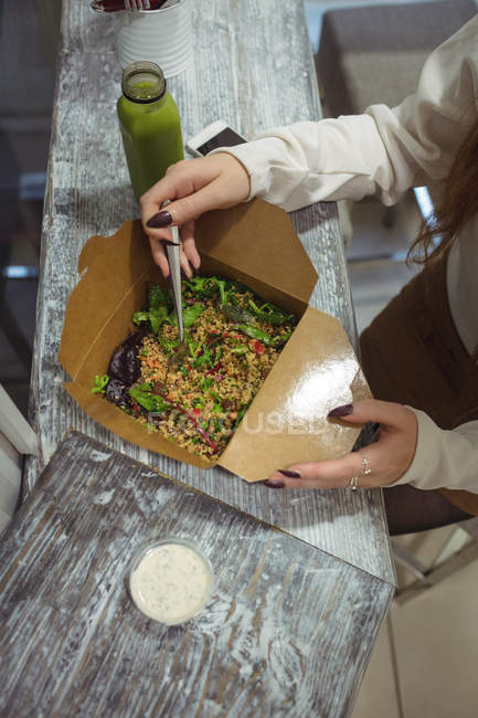 Високий кут зору жінки, що їсть салат у приміщенні — стокове фото