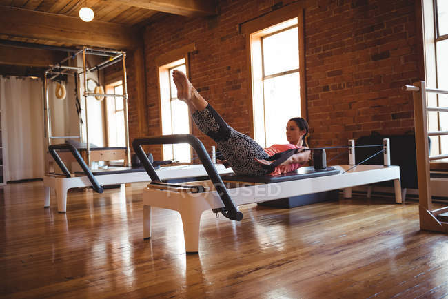 Mulher praticando pilates em reformador no estúdio de fitness — Fotografia de Stock
