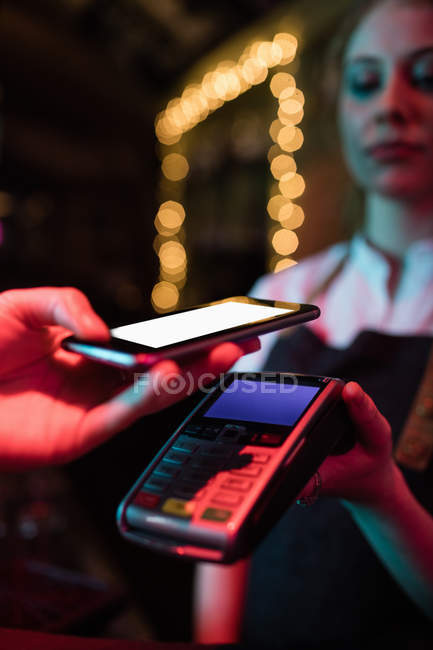 Cliente che effettua il pagamento tramite smart phone in bar — Foto stock