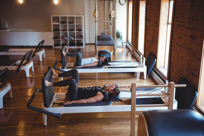 Женщины практикующие пилатес на реформаторах в фитнес-студии — стоковое фото
