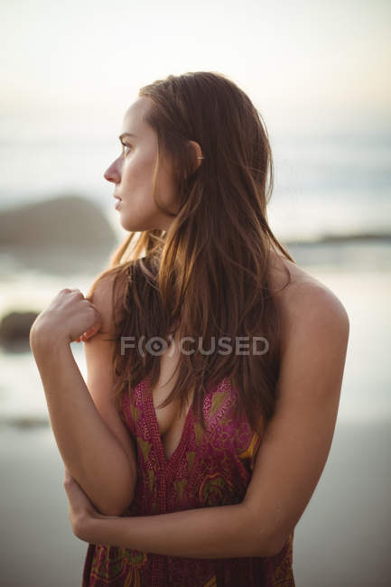 Продумана жінка стоїть на пляжі в сонячний день — стокове фото