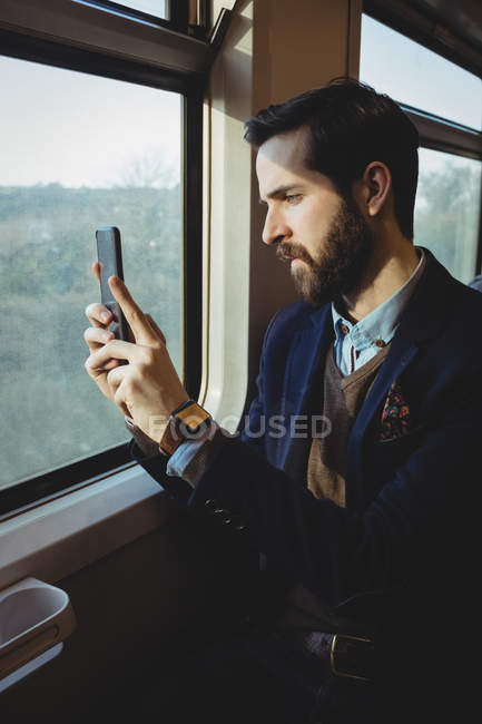 Empresario tomando fotos desde el teléfono móvil mientras viaja en tren - foto de stock