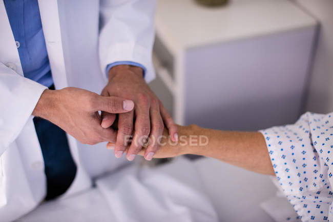 Male doctor comforting female senior patient in ward at hospital — Stock Photo