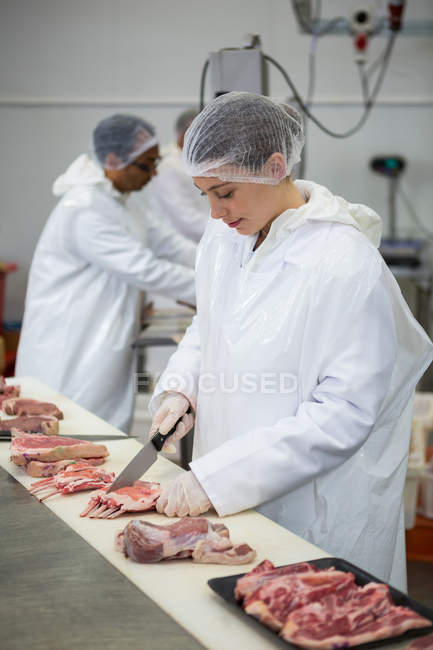 Fleischerin schneidet Fleisch in Fleischfabrik — Stockfoto