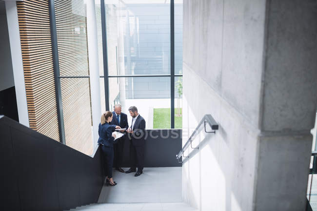 Gruppe von Geschäftsleuten diskutiert in der Nähe der Treppe im Büro — Stockfoto