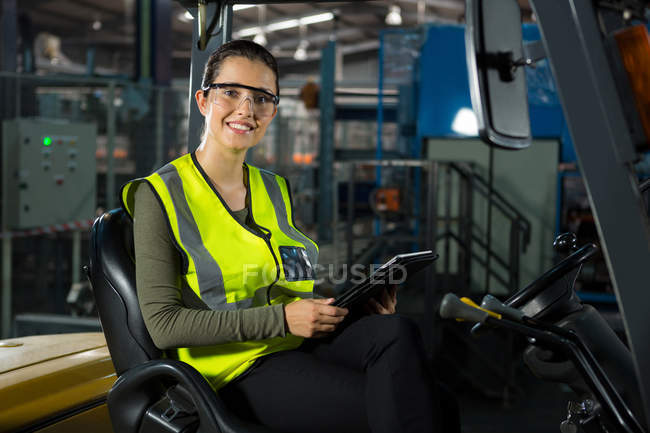 Retrato de bela trabalhadora com tablet digital em empilhadeira no armazém — Fotografia de Stock