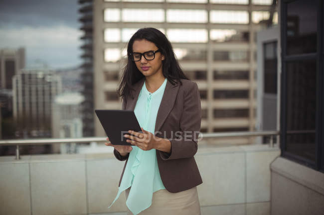 Mujer de negocios utilizando tableta digital en la terraza de la oficina - foto de stock
