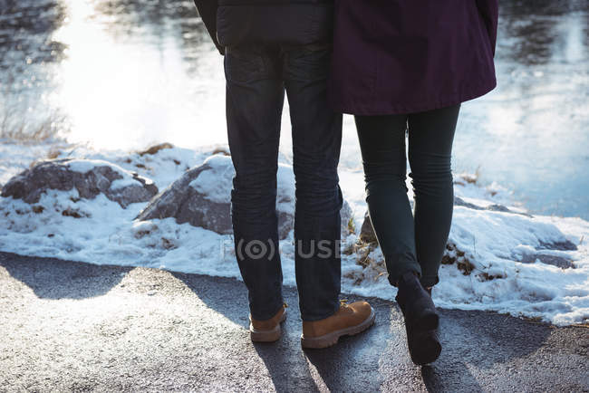 Низька частина романтичної пари, що стоїть біля річки взимку — стокове фото