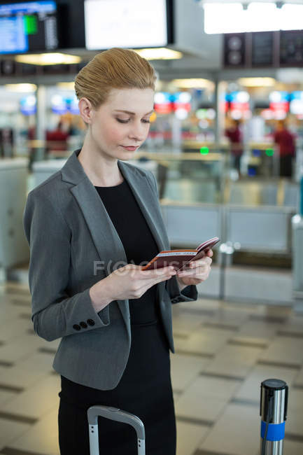 Geschäftsfrau mit Gepäck bei der Kontrolle ihrer Bordkarte im Flughafenterminal — Stockfoto