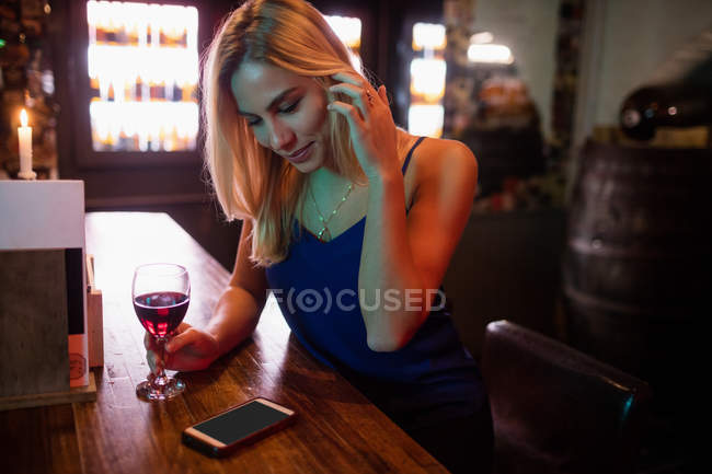 Жінка має келих червоного вина в барі — стокове фото