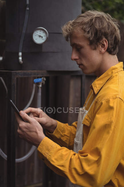 Man using digital tablet while making beer at home brewery — Stock Photo