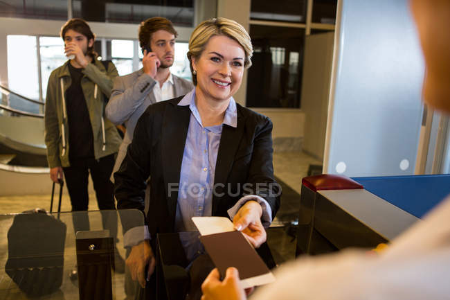 Donna d'affari che consegna la carta d'imbarco al personale femminile del terminal dell'aeroporto — Foto stock