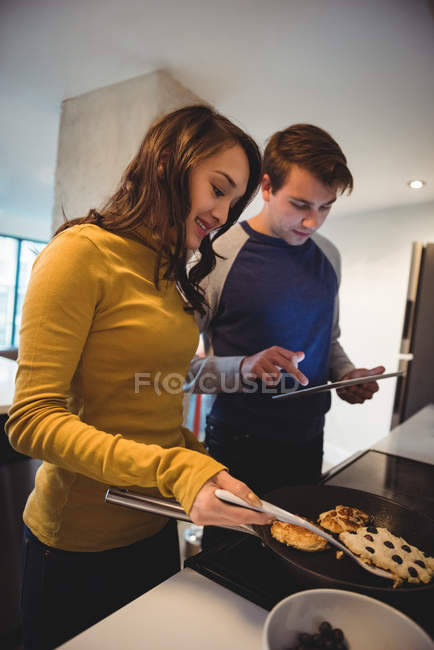 Пара використовує цифровий планшет під час приготування печива на кухні вдома — стокове фото
