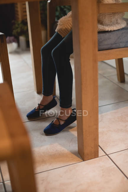 Low section of girl sitting on wooden chair at home — Stock Photo