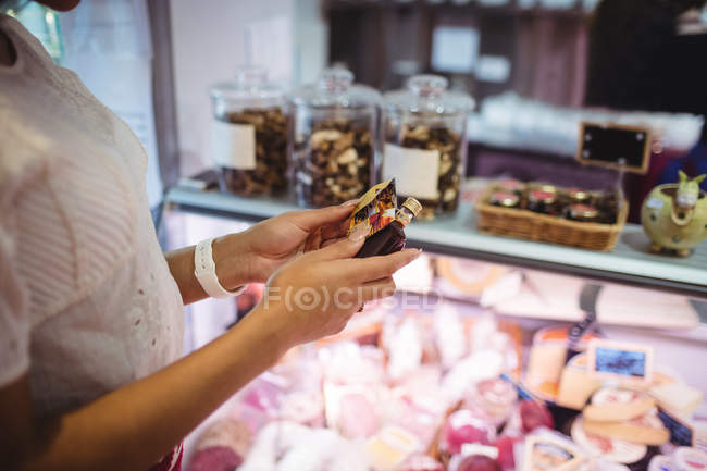 Woman looking at bottle in supermarket — Stock Photo