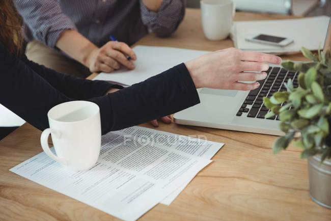 Seção intermediária de executivos de negócios discutindo sobre laptop no escritório — Fotografia de Stock