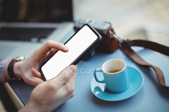 Mãos de executivo masculino segurando telefone celular enquanto toma café na cafetaria — Fotografia de Stock