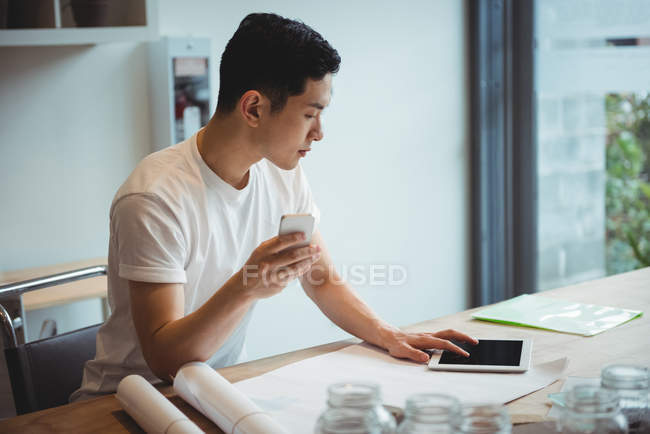 Business executive con tablet digitale e telefono cellulare in ufficio — Foto stock